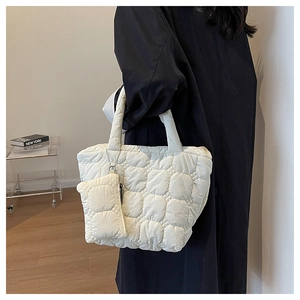 White quilted puffer tote bag with matching pouch shown on a model's shoulder in style
