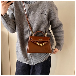 Vue détaillée du mini sac à main Kelly en cuir verni avec des accessoires métalliques.