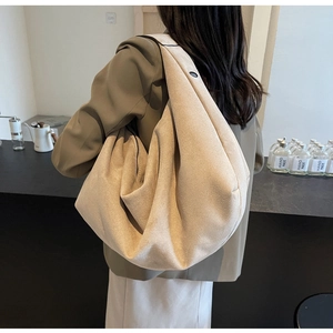 Détail d'un grand sac hobo en daim beige avec large bandoulière dans un café