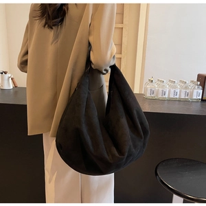 Vue détaillée d'un sac cabas en daim noir mat porté à l'épaule sur un mannequin féminin