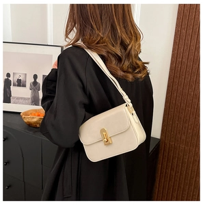 Dettaglio di una borsa a tracolla beige crema con chiusura a scatto rettangolare dorata