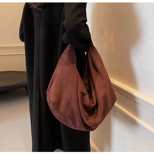 Vue détaillée du grand sac hobo en daim bordeaux porté à l'épaule sur un mannequin