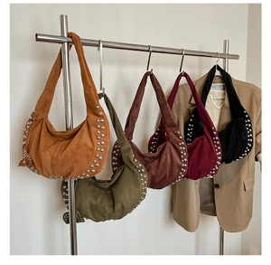 Détail de cinq sacs hobo en daim avec clous argentés sur un support de présentation mode