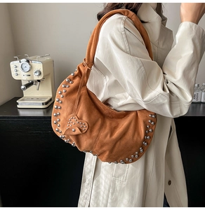 Detail van de bruine suède hobo tas met zilveren klinknagels en hartvormige hanger