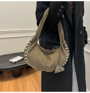 Détail du sac demi-lune en daim vert olive avec rivets argentés et pendentif cœur