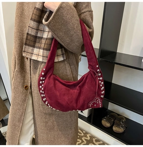Détail du sac demi-lune en daim bordeaux avec rivets argentés et ornement en forme de cœur