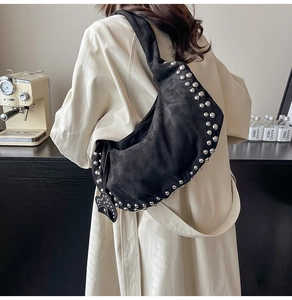 Détail du sac croissant en daim noir avec rivets argentés et pendentif noeud élégant