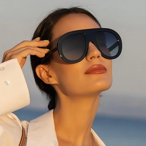 Fashion oversized black aviator sunglasses with gradient lenses worn by a model at sunset