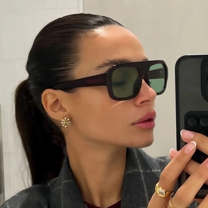 Gros plan de lunettes de soleil carrées avec verres verts portées par un mannequin