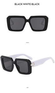 Detail of square sunglasses with black frame white temples and golden teardrop accent