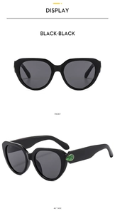 Front and 45-degree side views of black cat-eye sunglasses with green droplet stone