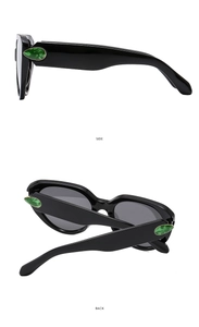 Detail view of black cat eye sunglasses featuring green teardrop side gemstones