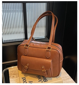 Detalle de bolso de cuero PU marrón con hebillas metálicas y bolsillo frontal cuadrado