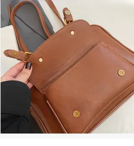 Detail of vintage brown leather briefcase bag with golden round buckle and stitching