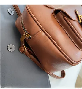 Close-up of caramel PU leather backpack featuring smooth golden metal zippers and stitching