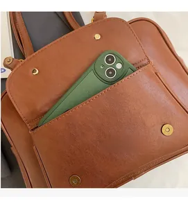 Detail of a brown leather backpack front pocket showing practical storage for a smartphone