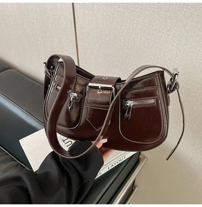 Detail of dark chocolate patent leather crescent bag with buckles and zippers