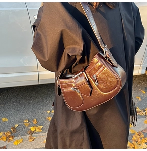 Detail of dark brown crinkled leather shoulder bag with moto-style zippers and silver hardware
