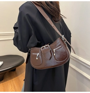Detail of dark brown faux leather underarm bag with silver buckles and zip pockets