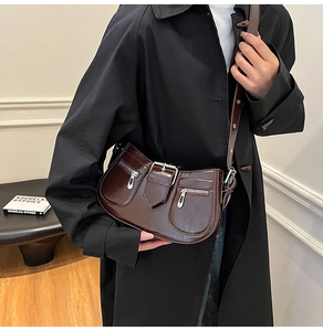 Detailed close-up of dark brown glossy patent leather bag with metallic buckle and silver zippers