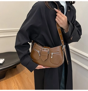 Detail of dark brown faux leather saddle bag with silver buckles and punk style zippers