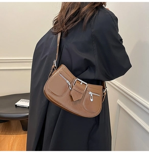 Brown leather saddle bag with silver buckle worn as a crossbody bag by a model