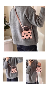 Detail of a pink polka dot mini crossbody bag with silver buckle and top handle