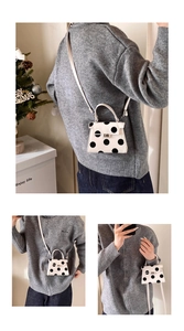 Detail showing white polka dot handbag with metal clasp lock and top handle design