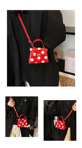 Detail of red polka dot mini bag featuring a sleek metal buckle and leather strap