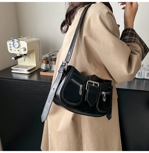Detail of black retro shoulder bag showing silver zippers and adjustable strap on a model