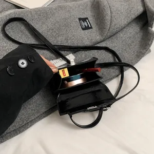 Interior view of black patent leather crossbody bag showing capacity for cosmetics