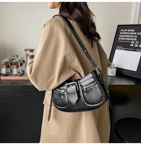 Detail of black glossy leather shoulder bag with vintage texture and silver buckles