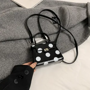 Detail shot of the black leather polka dot handbag with metal lock and round handle