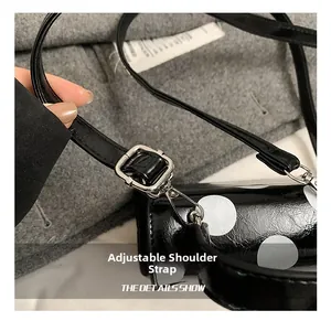 Close-up of adjustable strap with silver lobster clasp on a black polka dot handbag