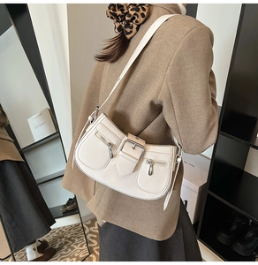 Close-up of retro cream underarm bag with silver zippers and belt buckle detail