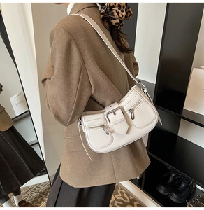 Detail view of cream vintage underarm bag with double zippers and metal buckle strap