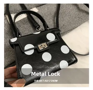 Detailed close-up of the metal clasp on a black polka dot mini crossbody handbag