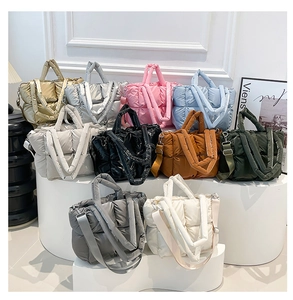 Multiple colors of quilted puffer tote bags displayed on a minimalist pedestal