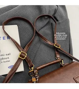 Detail of adjustable leather shoulder strap with gold buckle on brown vintage handbag