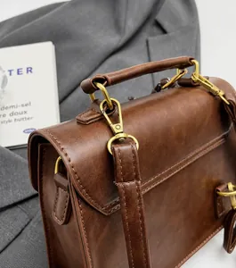 Detail of vintage brown leather handbag with luxury gold hardware and wax finish texture