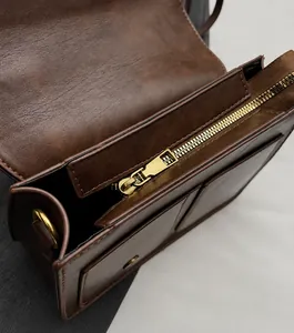 Detailed view of the dark brown leather bag showing inner metal zipper and front pocket