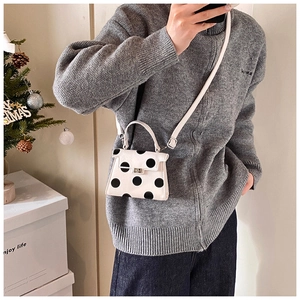 Chic polka dot mini bag with metal clasp shown in a mirror selfie for size reference