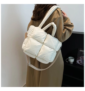 Detail shot of white quilted padded shoulder bag with adjustable strap worn on person