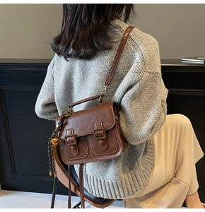 Detail of vintage brown leather satchel showing buckle closure and decorative pendant