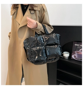 Detail of black glossy quilted puffer handbag with soft cylindrical top handles for women