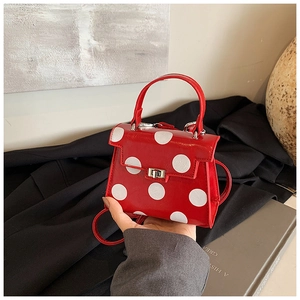 Detailed view of red polka dot mini bag with silver twist lock and smooth faux leather