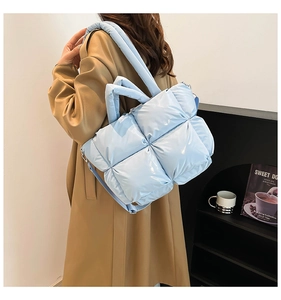 Detail view of light blue quilted down shoulder bag with glossy satin finish on coat