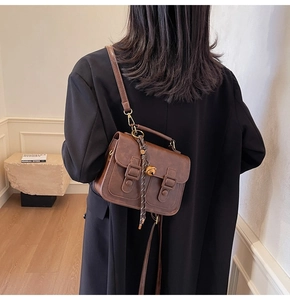 Rear view of model holding a vintage brown satchel with decorative metal charms