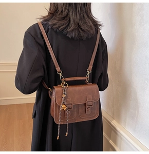 Detail of vintage coffee brown PU leather crossbody bag featuring dual magnetic buckles