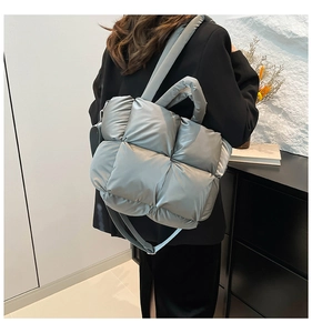 Silver quilted tote bag shown in a lifestyle setting with adjustable nylon shoulder strap